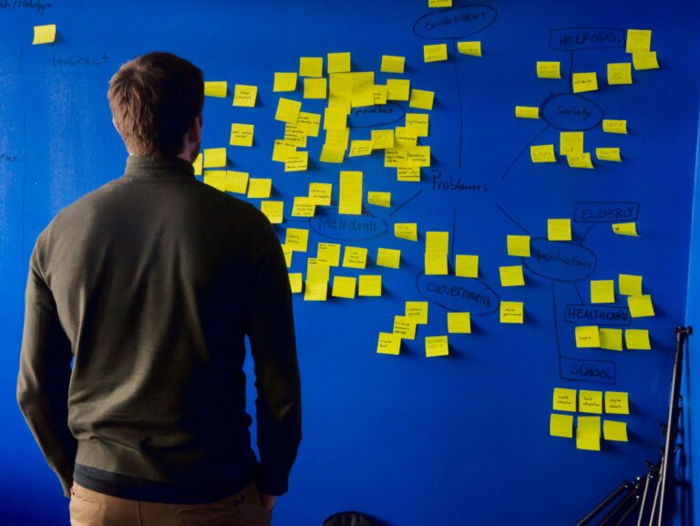 Ein Mann steht vor einem Board. Vor ihm kleben gelbe Post-its. Sie sollen ihm helfen, technische Produkte gut erklären zu können.